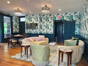A room with a sofa, chairs, a table, and a patterned wall.
