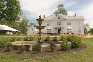 A large white building with a fountain in the front yard.