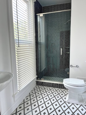 Ein Badezimmer mit einer weißen Toilette, einer Duschkabine und einem fußbodenbelag mit Muster.
