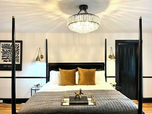Un dormitorio moderno con una cama grande, una araña y obras de arte en las paredes.