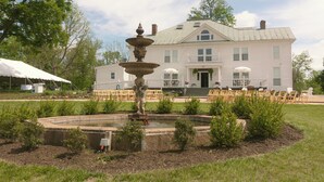 A large white building with a fountain in the front yard. - Everett Estate | King Suite + Twin Daybed (Nellysford)