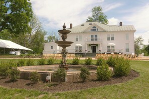 Ein großes, weißes Gebäude mit einem Brunnen im Vorgarten.
