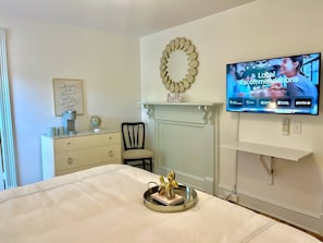 Ein Hotelzimmer mit einem Bett, einem Fernseher, der lokale Empfehlungen zeigt, einem Globus auf einer Kommode und einem dekorativen Spiegel an der Wand.