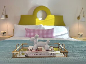 Un lit avec un oreiller à carreaux blancs et roses, une tête de lit jaune et une table de chevet avec une lampe.