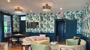 A room with a sofa, chairs, a table, and a patterned wall. - Everett Estate | Queen Suite + Covered Porch (Nellysford)