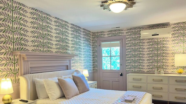A bedroom with a bed, bedside tables, a dresser, and a window. - Everett Estate | Queen Suite + Covered Porch (Nellysford)