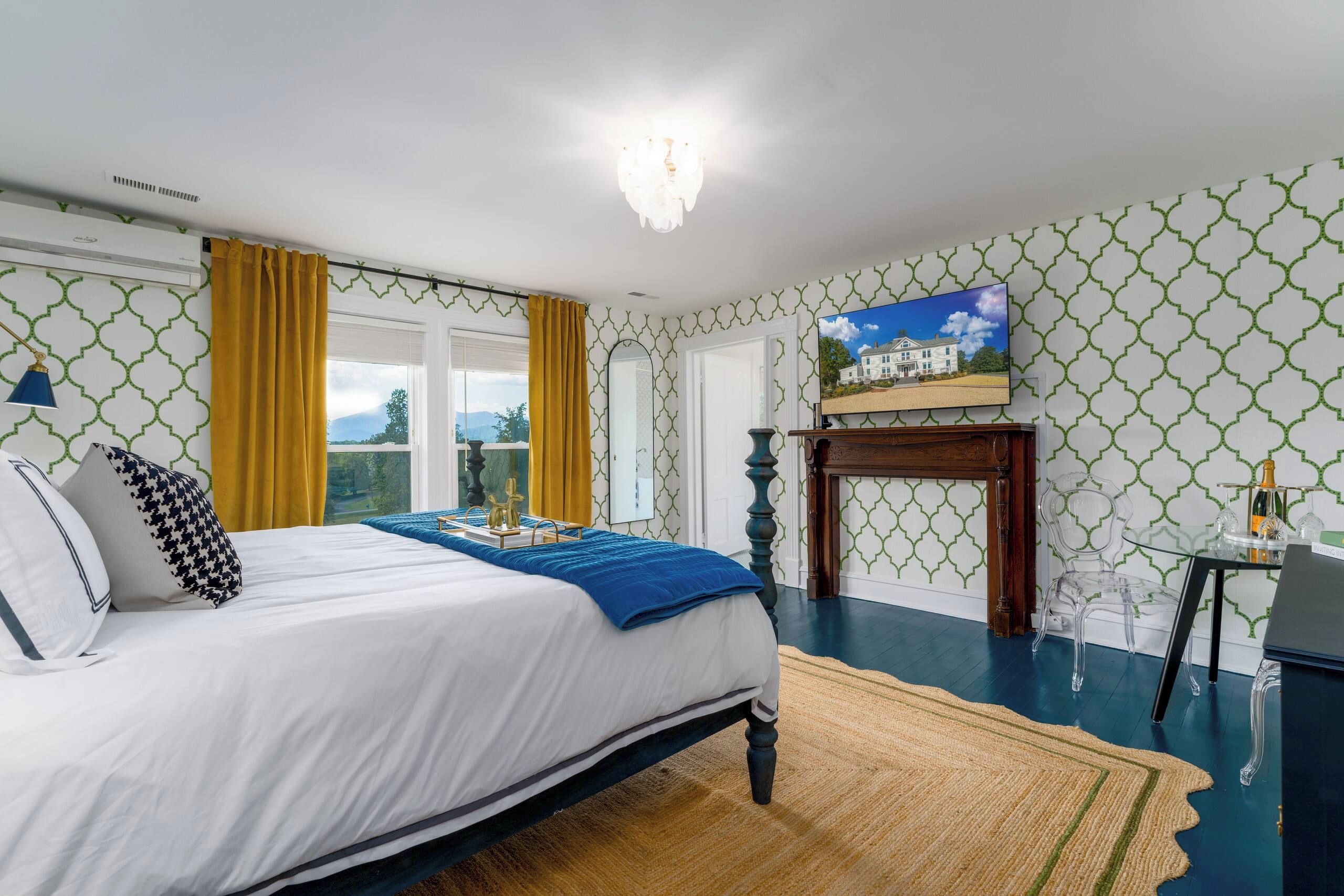 A bedroom with a bed, a TV, a fireplace, and a view of the outdoors.