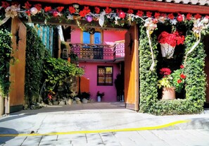 A building with a pink facade, a balcony with a metal railing, and potted plants. - Guelaguetza Terrace House, Oaxaca—10 minutes from downtown, ideal for families. (Oaxaca de Juárez)
