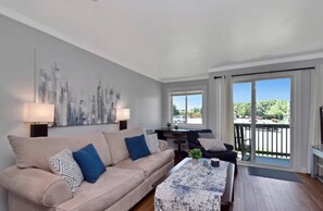 A living room with a beige sofa, patterned cushions, a coffee table, and a cityscape painting. - The Great Escape Pool/HotTub/Hike/Bike/Wineries! (Beech Mountain)