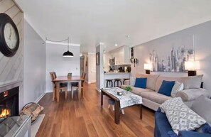 A modern living room with a fireplace, a dining area, and a kitchen in the background. - The Great Escape Pool/HotTub/Hike/Bike/Wineries! (Beech Mountain)