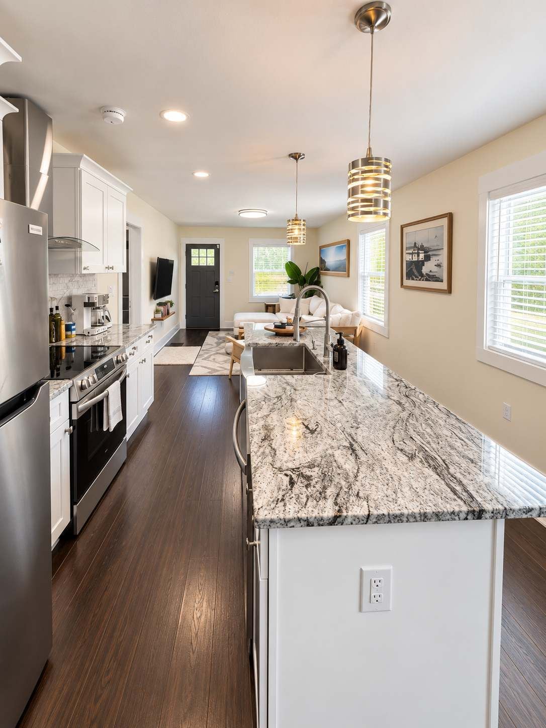 A modern kitchen with a marble countertop, stainless steel appliances, and pendant lighting.