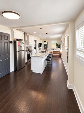 A modern kitchen with a central island, stainless steel appliances, and pendant lighting. - The Pad | Garage • EV • Fenced Yard • Walkable (Indianapolis)