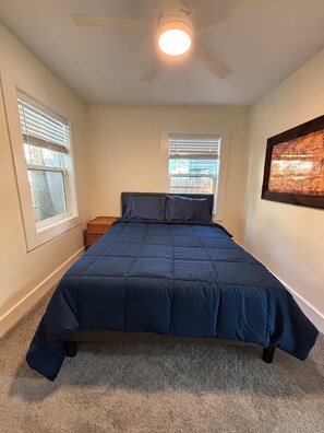 A bedroom with a bed, two windows, a ceiling fan, and a framed picture on the wall. - The Pad | Garage • EV • Fenced Yard • Walkable (Indianapolis)