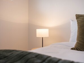 Una habitación de hotel con una cama, una mesita de noche y una lámpara.