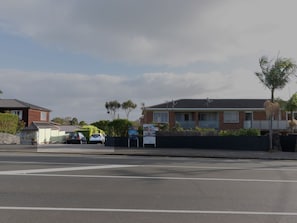 A residential street with houses, parked cars, and a 'SOLD' sign. - Sage & Sea by Homello (Auckland)