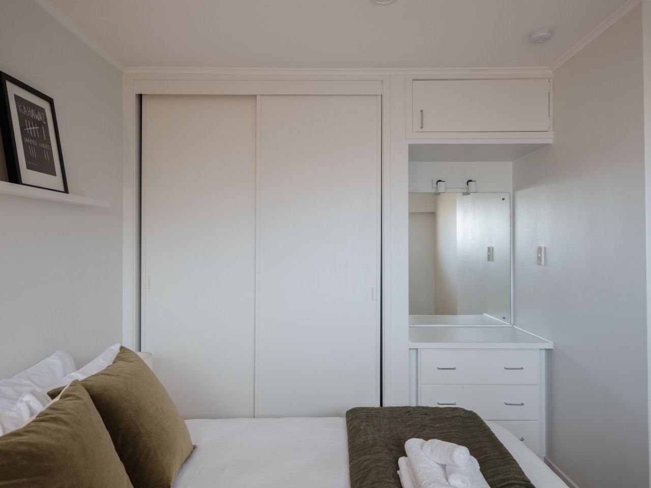 A bedroom with a bed, a wardrobe, a dresser, and a mirror.