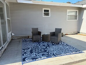 Un patio con dos sillas de mimbre y un tapete estampado.
