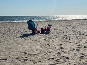 Una playa con dos sillas de playa y un bolso sobre la arena.