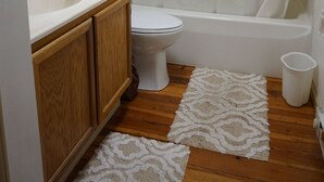 A bathroom with a toilet, sink, vanity, bathtub, and a shower curtain. - Secluded 2-bedroom house with PRIVATE RIVER ACCESS - Petersburg, WV (Petersburg)