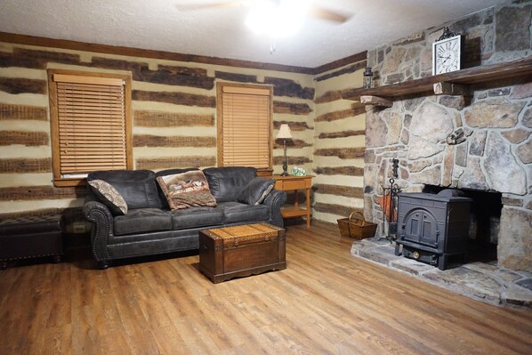 A cozy living room with a fireplace, a leather sofa, and a wooden floor.