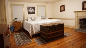 A bedroom with a bed, a dresser, a chest of drawers, a fireplace, and a window with blinds. - Secluded 2-bedroom house with PRIVATE RIVER ACCESS - Petersburg, WV (Petersburg)