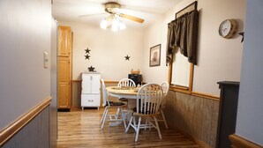 A narrow hallway with a wooden floor leading to a dining area with a round table and white chairs. - Secluded 2-bedroom house with PRIVATE RIVER ACCESS - Petersburg, WV (Petersburg)