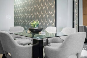 A modern conference room with a glass table, grey upholstered chairs, and a decorative plant centerpiece. - Lux Downtown Suite CN Tower Views with Parking | Parking Available (Toronto)