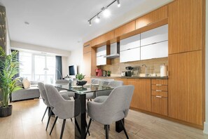 A modern kitchen with wooden cabinets, a glass dining table, and grey chairs. - Lux Downtown Suite CN Tower Views with Parking | Parking Available (Toronto)