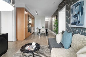A modern living room with a sofa, coffee table, and a dining area with chairs and a table. - Lux Downtown Suite CN Tower Views with Parking | Parking Available (Toronto)