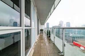 A corridor with glass walls, wooden flooring, and a view of a cityscape. - Lux Downtown Suite CN Tower Views with Parking | Parking Available (Toronto)