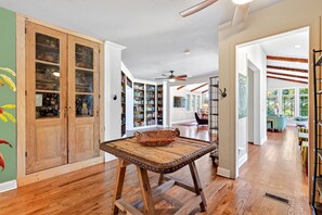 A spacious room with wooden flooring, a large wooden table, and a ceiling fan. - Queen Anne Victorian Home | Mountain Views + Minutes to Downtown Asheville! (Asheville)