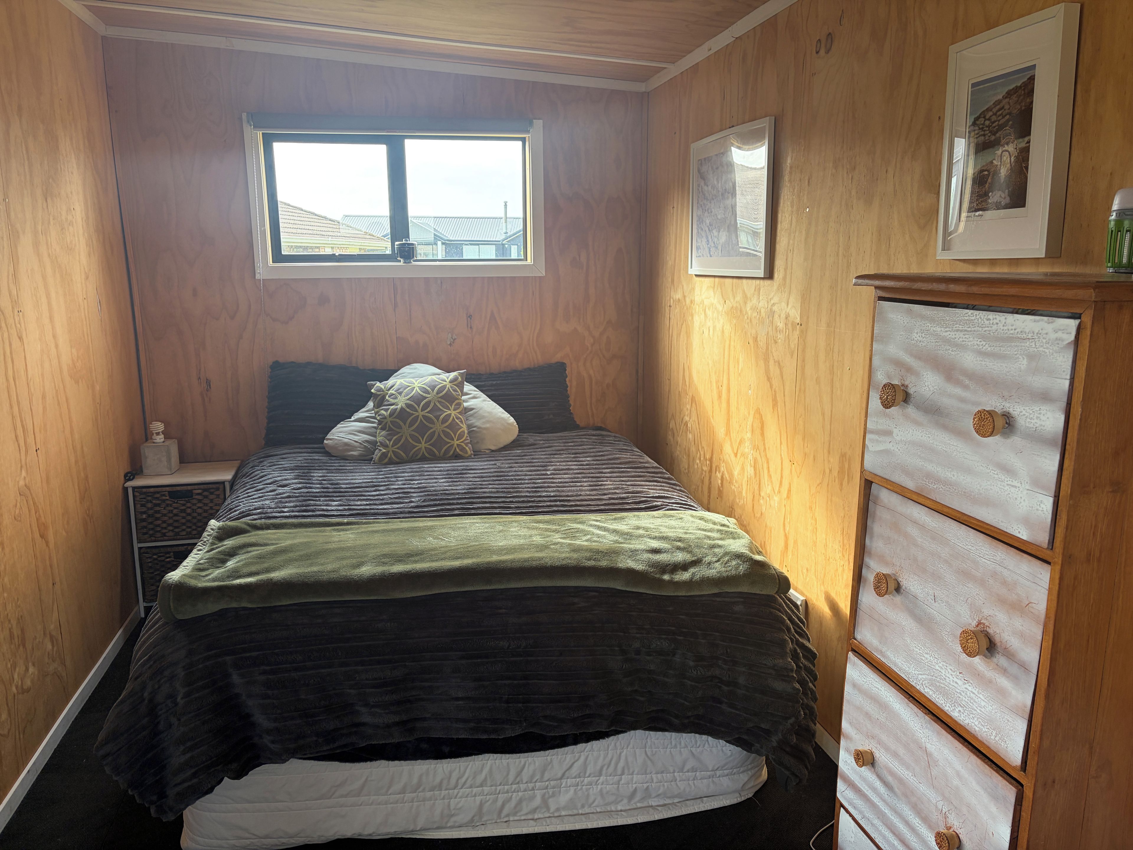 A bedroom with a bed, a dresser, a window, and a framed picture on the wall.