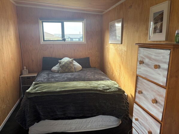 A bedroom with a bed, a dresser, a window, and a framed picture on the wall.