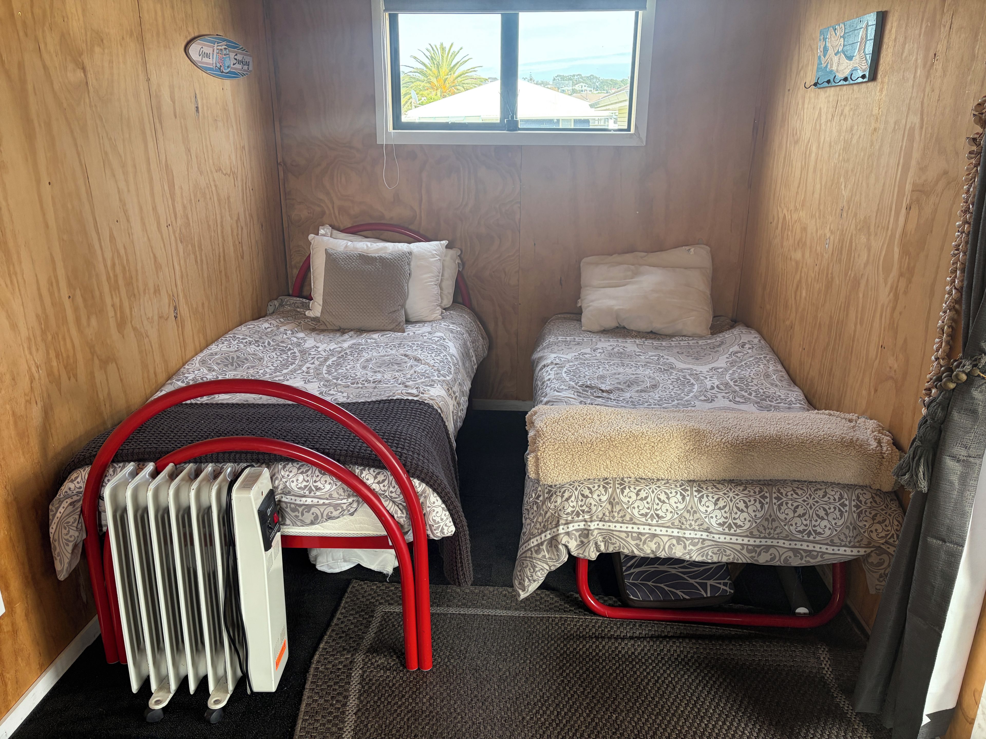 A compact room with two beds, a window, and a radiator.
