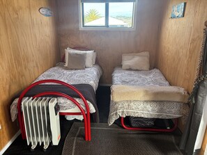 Habitación pequeña con dos camas, una ventana y un radiador.