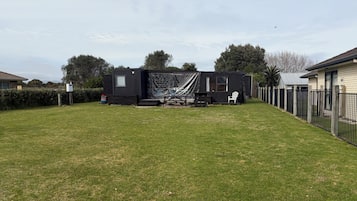 A residential property with a fenced yard, a small outdoor seating area, and a house with a dark exterior.