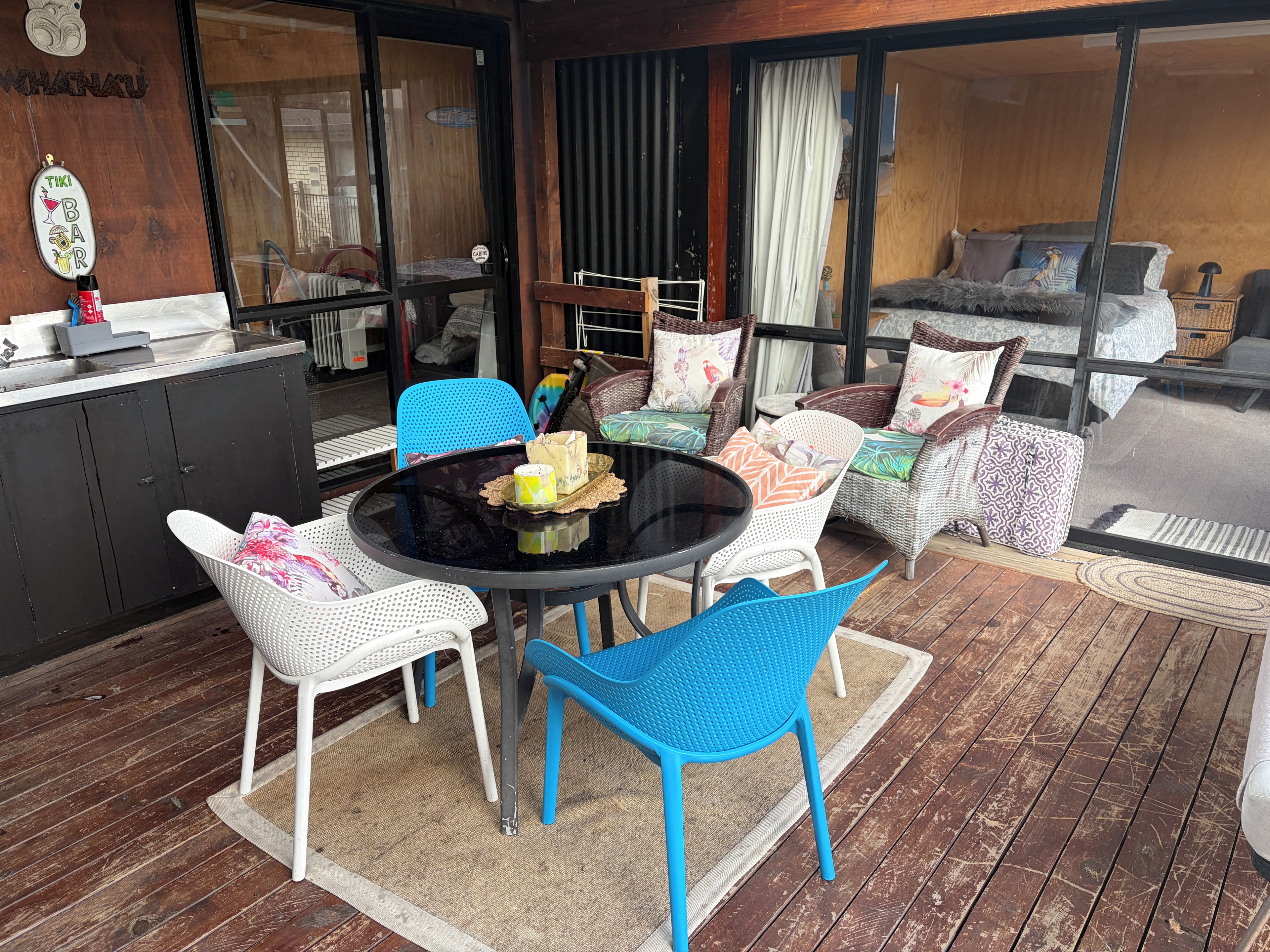 An outdoor seating area with a round table, blue and white chairs, wicker sofas, and a bar counter.