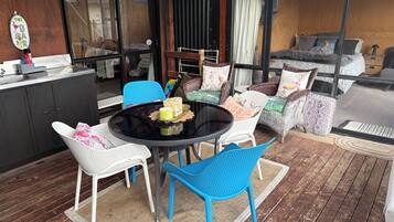 An outdoor seating area with a round table, blue and white chairs, wicker sofas, and a bar counter.