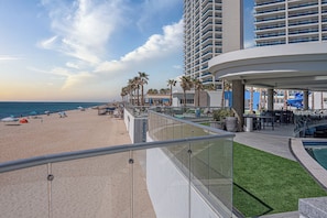 A beachfront hotel with a pool, outdoor seating, and a view of the beach. - Modern Oceanfront 1BR with Stunning Sea of Cortez Views (Puerto Peñasco)