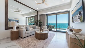 A modern living room with a sofa, coffee table, and a view of the ocean. - Modern Oceanfront 1BR with Stunning Sea of Cortez Views (Puerto Peñasco)