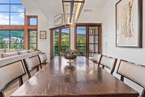 Een eetkamer met een grote houten tafel, stoelen en een schaal decoratieve objecten.
