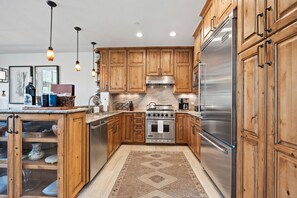 A kitchen with wooden cabinets, stainless steel appliances, and pendant lighting. - Spacious 4BR Beaver Creek Ski In Ski Out Townhome (Beaver Creek)