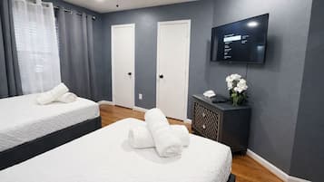 Een hotelkamer met twee bedden, een televisie, een klein tafeltje met een bloemenvaas en een tv aan de muur.