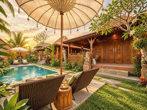 A poolside area with wicker furniture, a wooden structure, and a statue. - Traditional Joglo Pool Villa, Ubud (Ubud)
