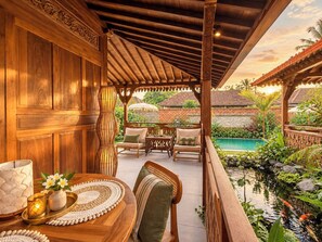 A wooden outdoor seating area with a pool and lush greenery. - Traditional Joglo Pool Villa, Ubud (Ubud)