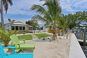 Propiedad residencial con patio, mobiliario exterior y vista al agua.