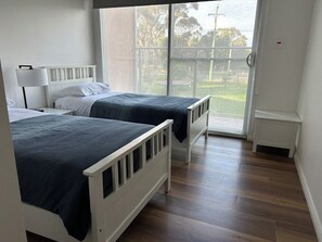 A hotel room with two beds, a window, and a view of the outdoors. - Spacious modern house in coastal bushy location 2 minutes to beach and town (Bicheno)