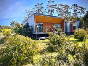 A modern two-story house with a wooden deck and large windows. - Spacious modern house in coastal bushy location 2 minutes to beach and town (Bicheno)
