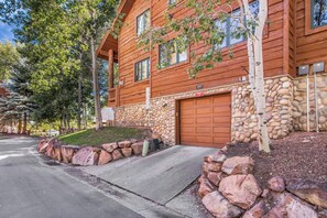 A log cabin with a stone foundation, a garage, and a driveway. - Timber Wolf 11B | Creekside | Canyons Village | Hot Tubs | Fireplace | Free Bus (Park City)