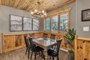 A dining area with a wooden table and chairs, a chandelier, and framed artwork on the wall. - Timber Wolf 11B | Creekside | Canyons Village | Hot Tubs | Fireplace | Free Bus (Park City)